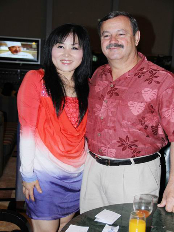 A Chinese woman posing for a photo beside a Caucasian man.